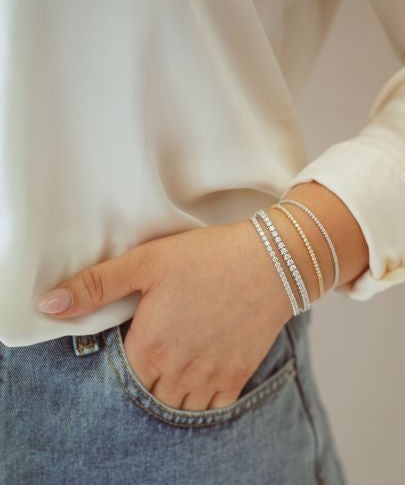 Woman wearing four lab diamond tennis bracelets.