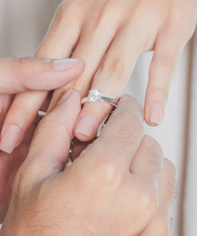 Man placing an engagement ring on woman's finger.